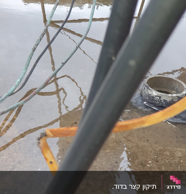 כבלים חשמליים על רצפה רטובה עם שלולית